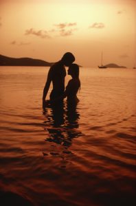 Romantic couple in ocean silhouetted by sunset - Because writing romance is easier than nonfiction blogging during coronavirus quarantine